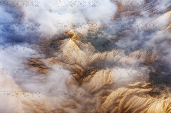 Stunning aerial view of rocky mountain peaks partially obscured by white clouds The landscape reveals a dramatic contrast between jagged ridges and soft mist