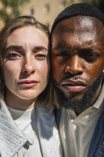 Vertical close-up of two multi-ethnic people cheek to cheek looking at camera