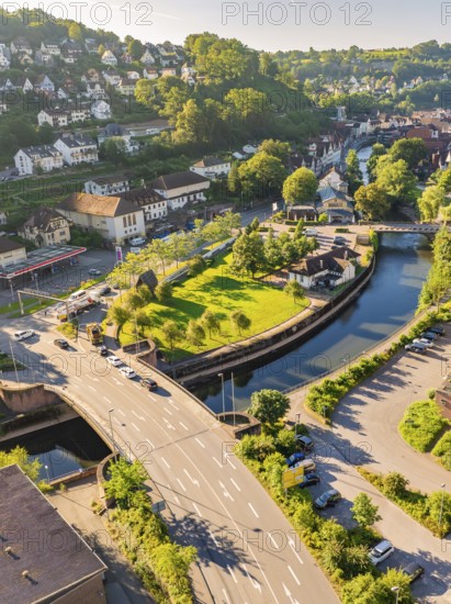 Aerial view of a bridge over a canal in a town with green spaces and many trees in daylight, Calw, Black Forest, Germany