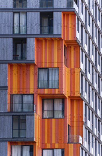 Detail of modern architecture blending glass, concrete, and metal in a suburb high-rise building, showing orange and gray exteriors