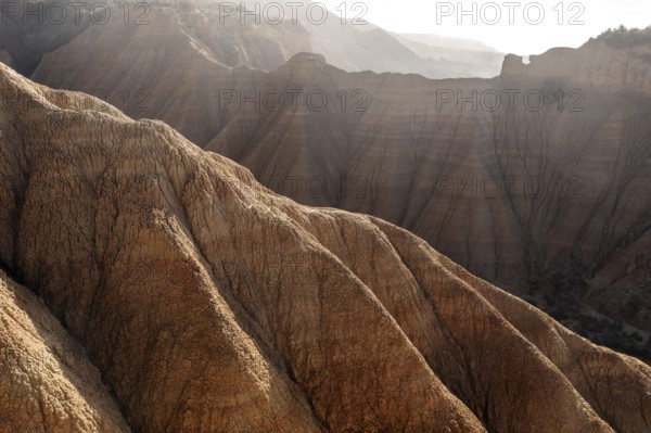 A stunning aerial view of a rugged mountain landscape with sharp ridges and soft light casting dramatic shadows, showcasing the raw beauty of nature's formations