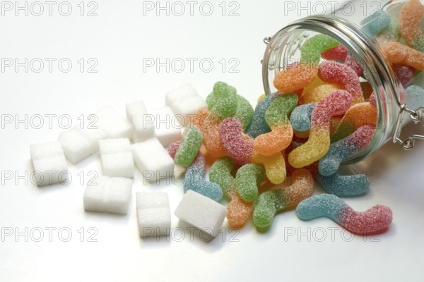 Lots of colorful jelly sweets in glass containers and sugar cubes, sugar consumption