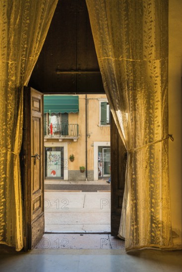 View from a room through curtains onto the street, Lazise, Italy