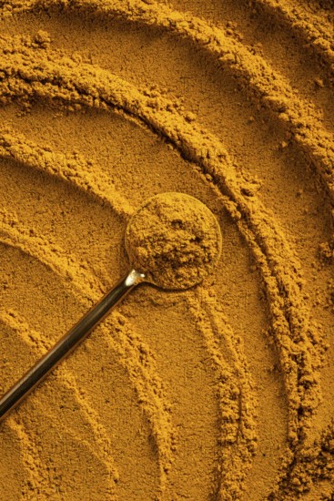 A vibrant close-up of golden curry powder, showcasing its textured surface with swirling patterns This aromatic spice is perfect as an ingredient for cauliflower curry soup and more