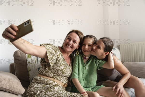 A joyful family is gathered on the couch, taking a selfie with a young girl who has a tracheostomy. The atmosphere is warm and loving, reflecting togetherness and inclusion