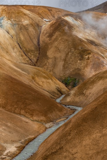 Steaming stream between colourful rhyolite mountains, Hveradalir geothermal area, Kerlingarfjöll, Icelandic highlands, Iceland