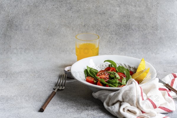 A refreshing arugula and herb salad, elegantly garnished with Himalayan salt, olive oil, cherry tomatoes, and seeds, creating a delightful mix of flavors and textures