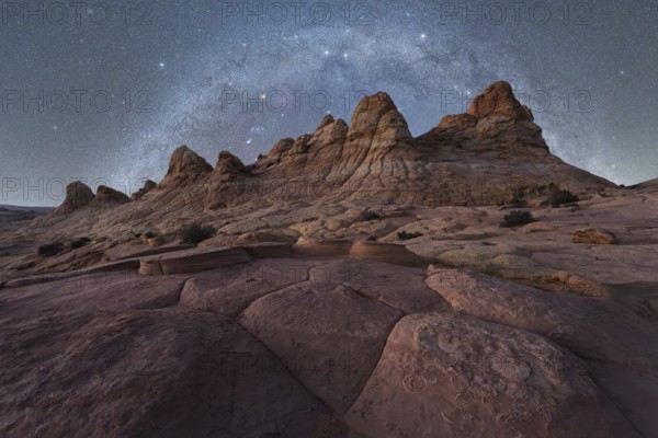 A breathtaking view of jagged rock formations under a vast, starry night sky, capturing the beauty of a remote desert landscape in Coyote Buttes, Arizona. Perfect for nature and travel enthusiasts