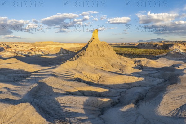 A panoramic view of dramatically eroded sandstone formations under the warm light of a setting sun in the rugged landscape of Utah, showcasing nature's intricate sculpting