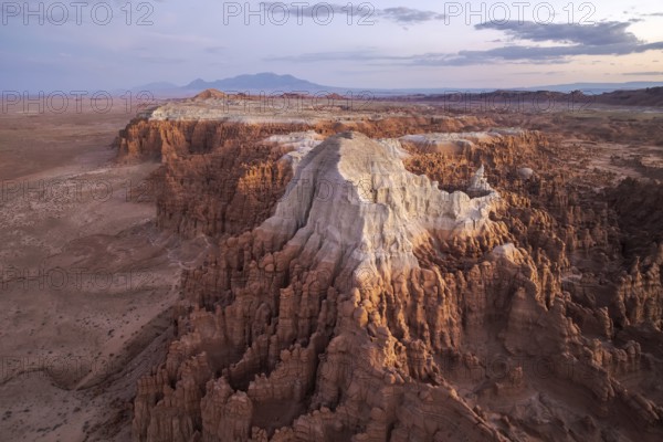 Captivating aerial shot of Goblin Valley State Park in Utah, showcasing its intricate landscape and towering rock formations under a fading sunset, creating a surreal, otherworldly panorama
