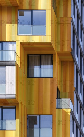 The vibrant and modern architecture in the suburbs, showcasing a mix of glass, concrete, and metal elements. The building's surfaces feature a striking palette of oranges and grays