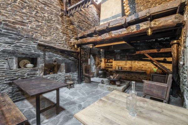 Traditional stone-walled kitchen inside an old country house in Lugo, Spain, featuring wooden beams, vintage furniture, and rural decor