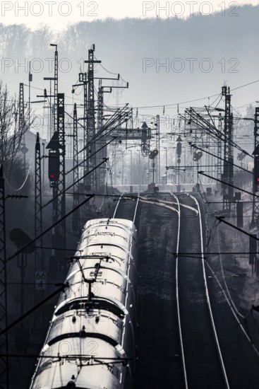 Deutsche Bahn AG tracks with ICE train against the light. Overhead line, signals and infrastructure. Railway tracks at the Geislinger Steige, Alb ascent to the Swabian Alb. Amstetten, Baden-Württemberg, Germany