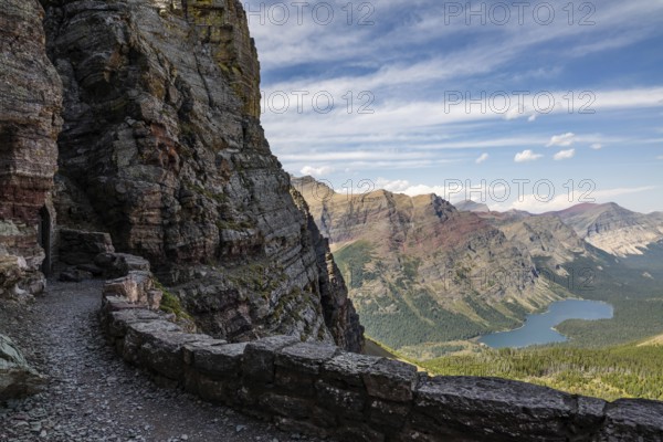 Rugged mountain landscape of Glacier National Park in Montana, showcasing dramatic cliffs, lush valleys, and a serene lake under a vibrant blue sky, perfect for adventure seekers