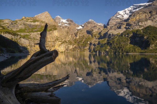 A breathtaking view of Oachinensee in Switzerland, showcasing mountains mirrored in the tranquil lake. The serene atmosphere and rugged landscape captivate the essence of nature
