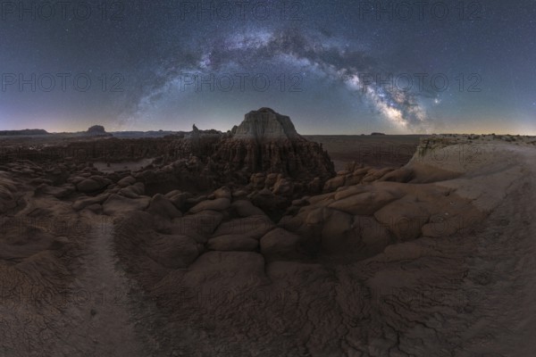A breathtaking panorama of the Milky Way arcing over the uniquely eroded rock formations of Goblin Valley State Park in Utah, captured in a serene desert landscape at nighty with the natural sculptures of the park