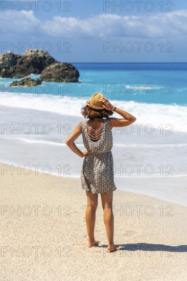 A woman walking on the turquoise water Megali Petra beach of Lefkada island, Ionian Sea, Greece