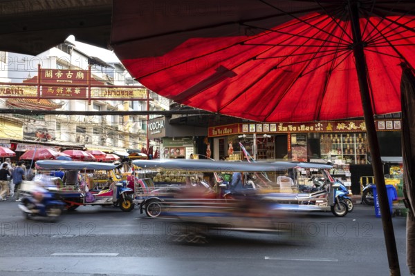 Bangkok, Thailand. March 25th 2025. Busy evening traffic of tuk-tuk and taxis passing popular street food stalls along Yaowarat Road, Chinatown, Bangkok, Thailand