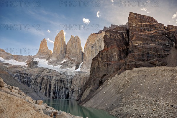 Dramatic mountain landscape with towering cliffs and a small lake in the foreground, The rock towers of Torres del Paine in Patagonia Chile