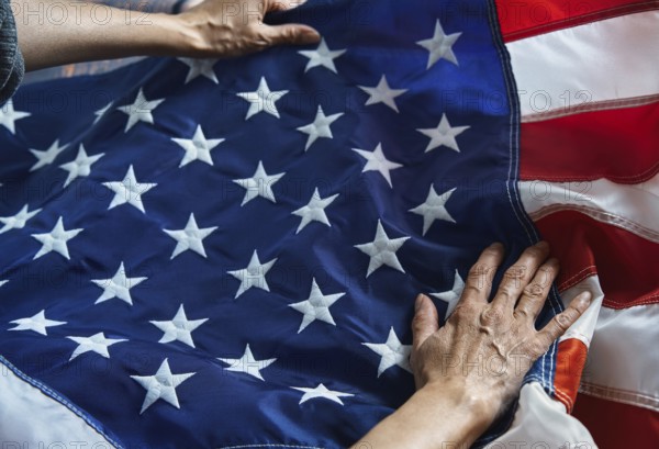 Hands gently hold the American flag, with its iconic stars and stripes. This image symbolizes patriotism, unity, and pride, capturing the essence of national identity and respect