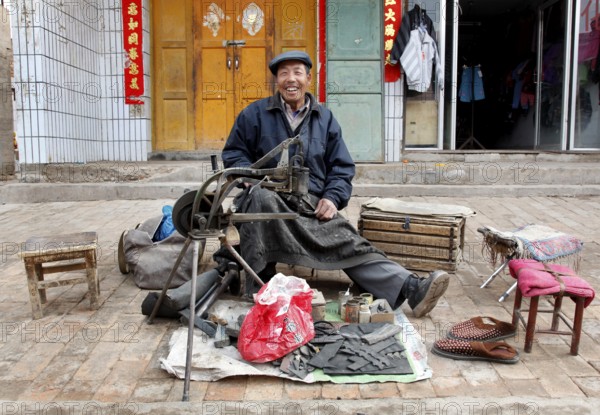 Xining, CHN, 27.02.09 - portrait of a Chinese shoemaker. Portrait picture of a roadside cobbler in a village near Xining, CHINA
