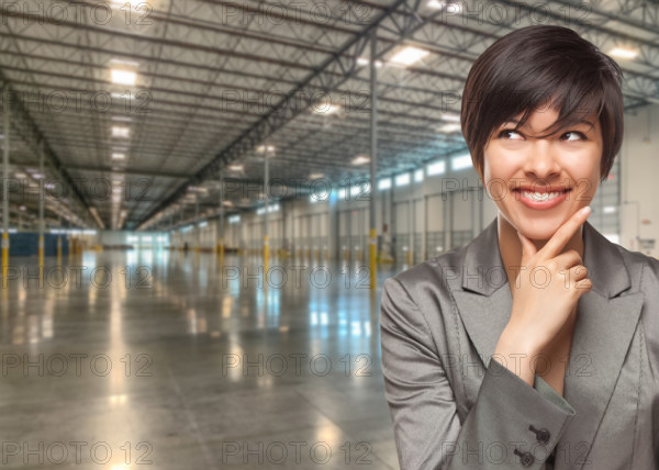 Thinking Mixed Race Businesswoman Standing in Empty Industrial Warehouse