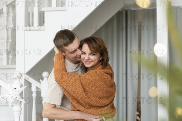 A warm and affectionate scene with a man and a woman sharing a loving embrace in a beautifully decorated home during Christmas, exuding happiness and holiday cheer