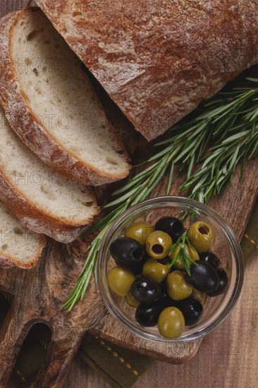 Sliced ciabatta, on a chopping board, with rosemary and olives, Italian bread, close-up, Italian cuisine, breakfast, no people