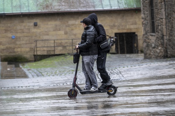 City center, shopping street, Kettwiger Straße pedestrian zone in Essen, 2 young men on an e-scooter, electric scooter, rainy weather, North Rhine-Westphalia, Germany