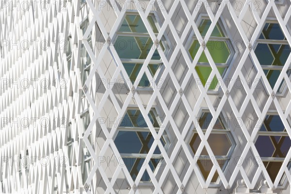 Abstract view of a auditorium facade showcasing geometric patterns of interlocking diamond shapes and hexagonal windows. The modern design highlights symmetry and innovation
