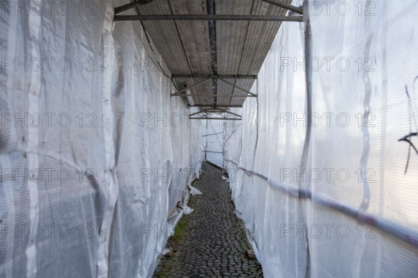 Footpath through a scaffolding with tarpaulin, Fußweg durch ein Baugerüst mit Abdeckplane