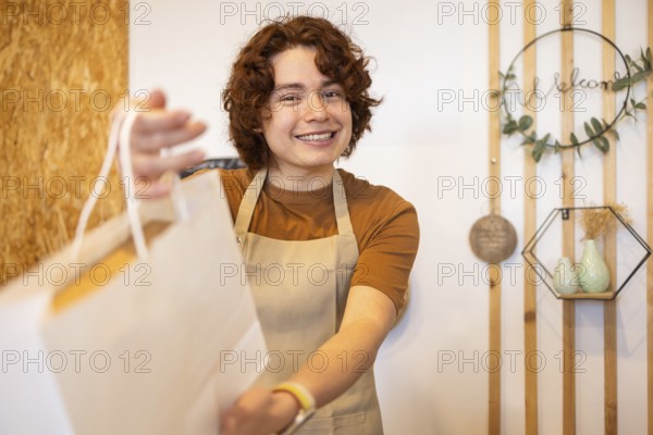 A cheerful shop assistant in an apron hands a paper bag to a customer, creating a warm and welcoming atmosphere in an eco-friendly boutique Wooden decor adds a rustic touch