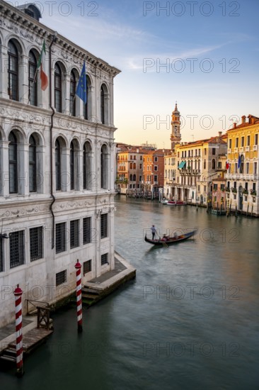 View of the Grand Canal with gondoliers at sunset, picturesque evening mood with palazzos on the canal and church tower of the Chiesa Parrocchiale dei Santi Apostoli, long exposure, view from the Rialto Bridge, Venice, Veneto, Italy