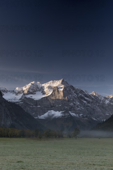 Nature conservancy area Grosser Ahornboden. Sycamore maple trees, Acer pseudoplatanus, in autumn. Karwendel mountains in the back with blue sky