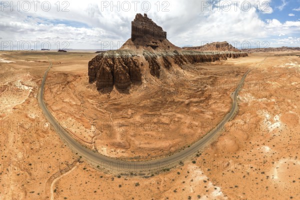 Panoramic aerial view of Goblin Valley State Park in Utah featuring rugged landscapes, unique rock formations, a winding road, and expansive desert terrain under a cloudy sky