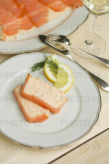 Southern German cuisine, salmon trout terrine arranged on a plate, salmon terrine with trout fillets, fish dish, salmon fillets, smoked salmon, starter, fine dining, Sunday crockery with gold rim, grandma's service, lemons, dill, fish cutlery, food photography, studio, Germany
