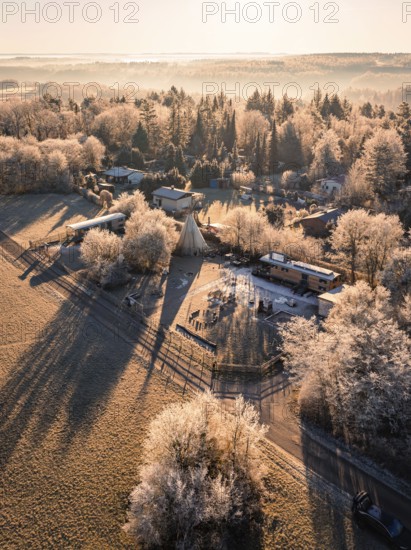 Village with trees and tepee, frozen landscape in warm morning light, day care centre, Gechingen, Hecken and Gäu region, district of Calw, Black Forest. Germany