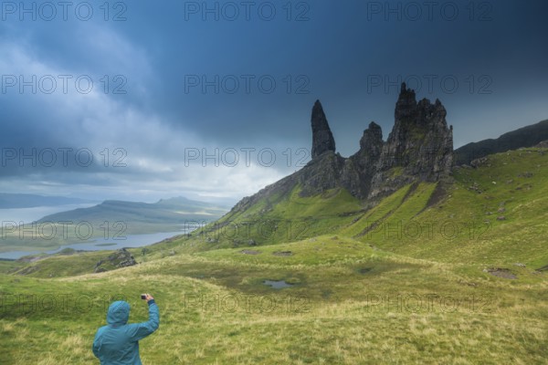 UK. Scotland. Isle of Skye. A tourist taking a picture of the Old Man of Storr during a storm