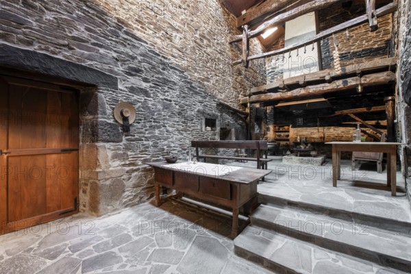 An authentic rustic kitchen featuring stone walls and wooden beams in a historical country house in Lugo, Spain, with vintage furniture and traditional decor
