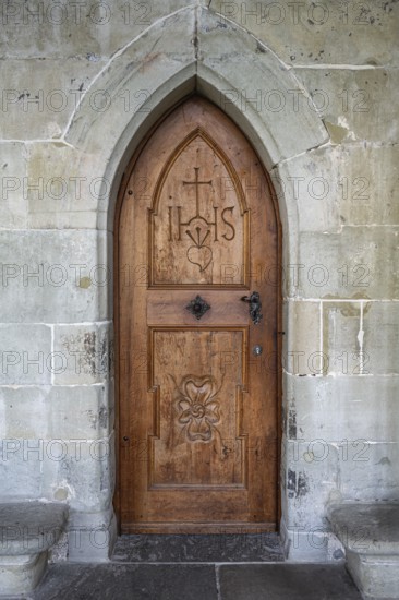 Wooden door with carvings and religious symbols in stone arch, Gothic architecture in the cloister of Constance Cathedral, traditional craftsmanship, Constance, district of Constance, Baden-Württemberg, Germany