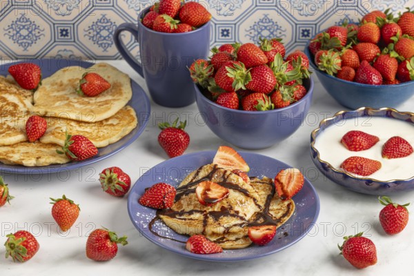 Pancakes with strawberries Chocolate syrup next to fresh strawberries and yoghurt in blue crockery