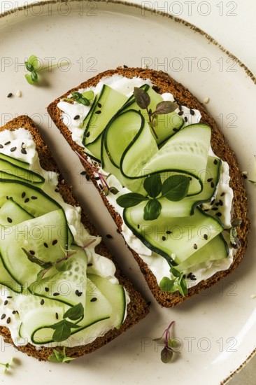 Breakfast, cereal bread sandwiches, cream cheese, sliced cucumber, with micro greenery on a light table, close-up, top view, selective focus, no people