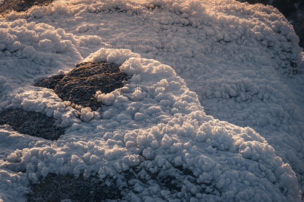 Closeup of snow covered rocks in the Siete Picos, Sierra de Guadarrama, Madrid. The winter sun casts a warm glow on the texture of the snow, highlighting the beauty of nature