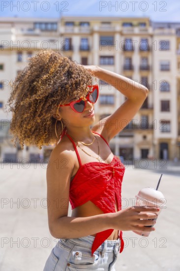Vertical side view portrait of a sensual woman in summer clothes drinking shake in the city