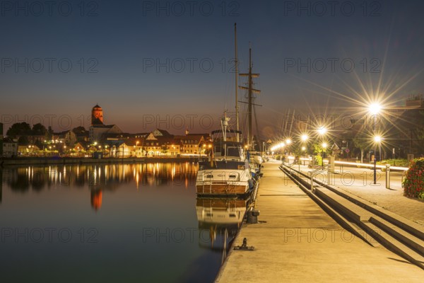 Sailing boats in the port of Wolgast at dusk, blue hour, in the back the old town with St. Peter's Church, Wolgast, Mecklenburg-Western Pomerania, Germany