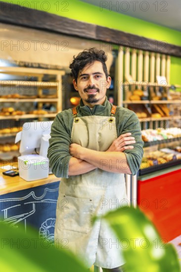 Vertical portrait of a latin male artisan baker standing proud in the shop of new business