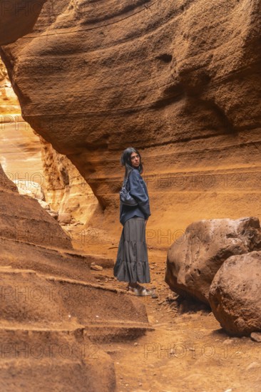 Tourist walking through the unique rock formations of barranco de las vacas, a stunning canyon in gran canaria, spain, enjoying the beauty of nature
