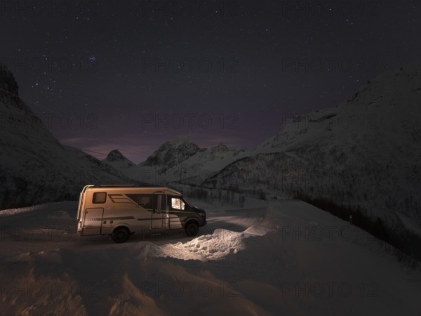 Winter motorhome under a starry sky on the island of Senja in a serpentine, Troms, Norway