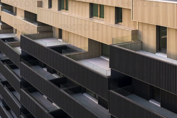 This image showcases a modern apartment building characterized by vibrant colorful portals and a sustainable design aimed at low emissions and high efficiency, epitomizing passive house standards