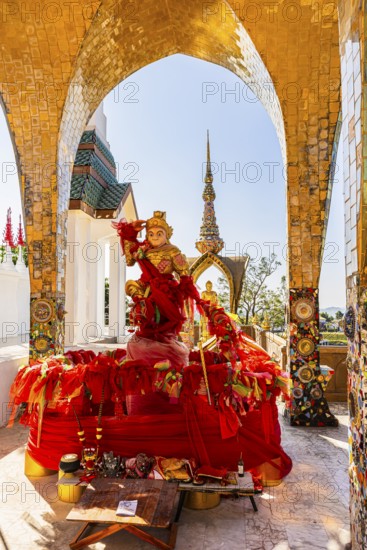 Round arch pavilions decorated with colorful mosaics and glass works of art, including a gilded statue on a red base, Buddhist temple complex Wat Phra That Sorn Kaew, Phetchabun province, Thailand